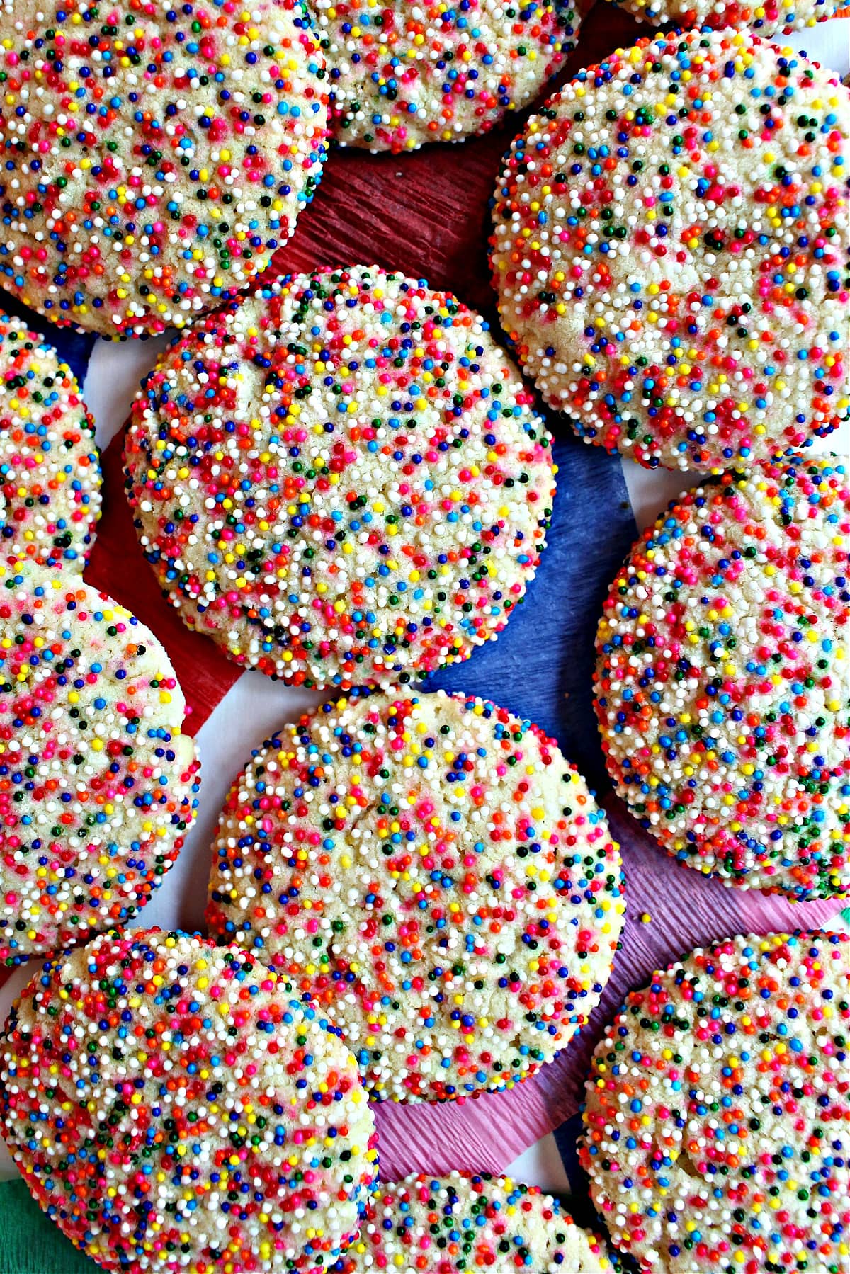 Large, round sugar cookies coated in rainbow colored nonpareil sprinkles.