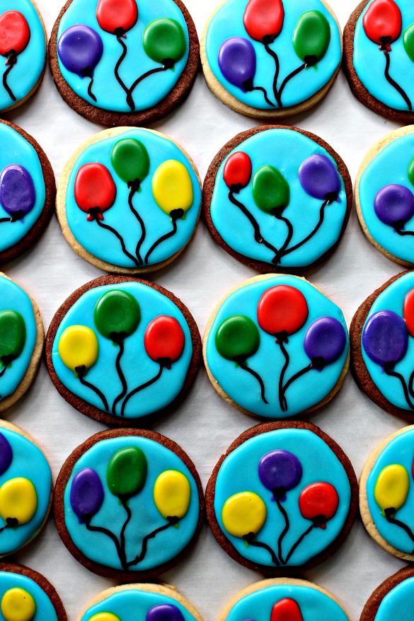 Balloon Sugar Cookies are circle sugar cookies with a sky blue icing background and 3 colored, circle balloons with black strings on each cookie.