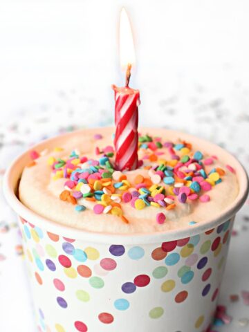 Individual Birthday Mug Cake with a lit candle on top.