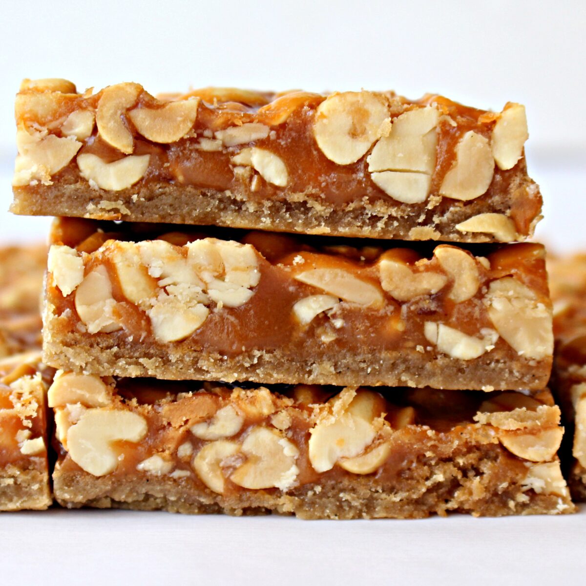 Stacked Peanut Bars showing shortbread crust topped with butterscotch and peanuts.