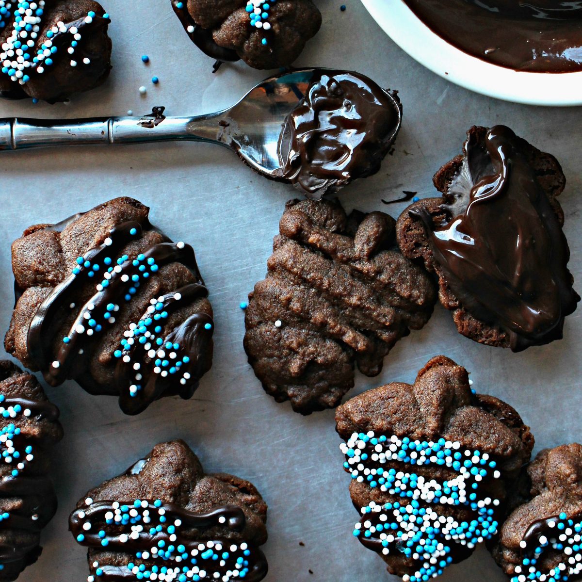 Closeup of dreidel press cookies being sandwiched with melted dark chocolate.