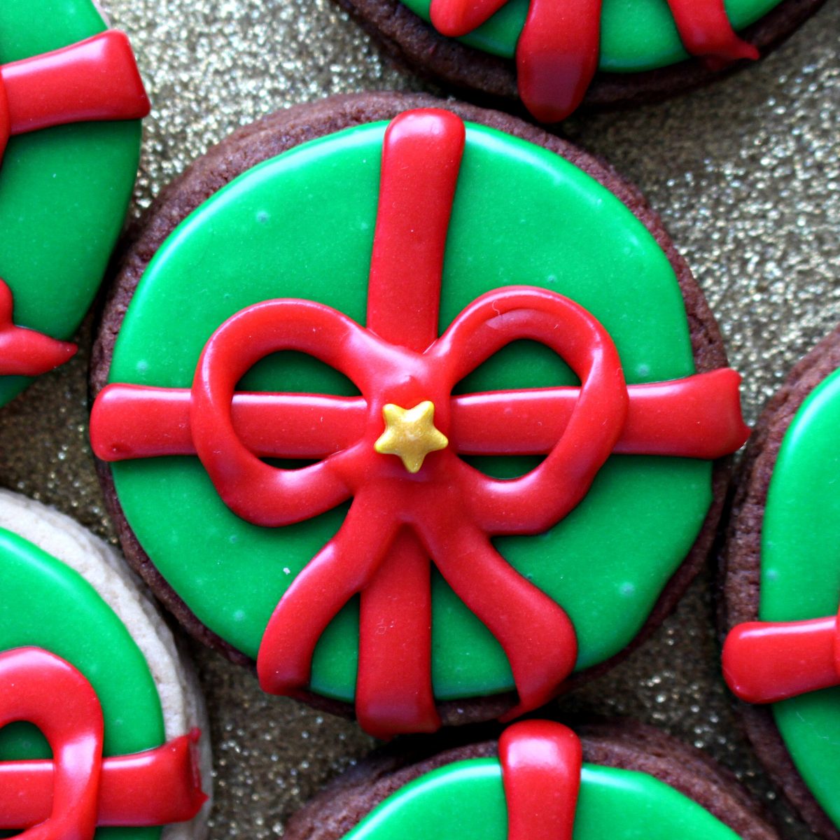 Closeup of cookies iced green with a red icing bow.