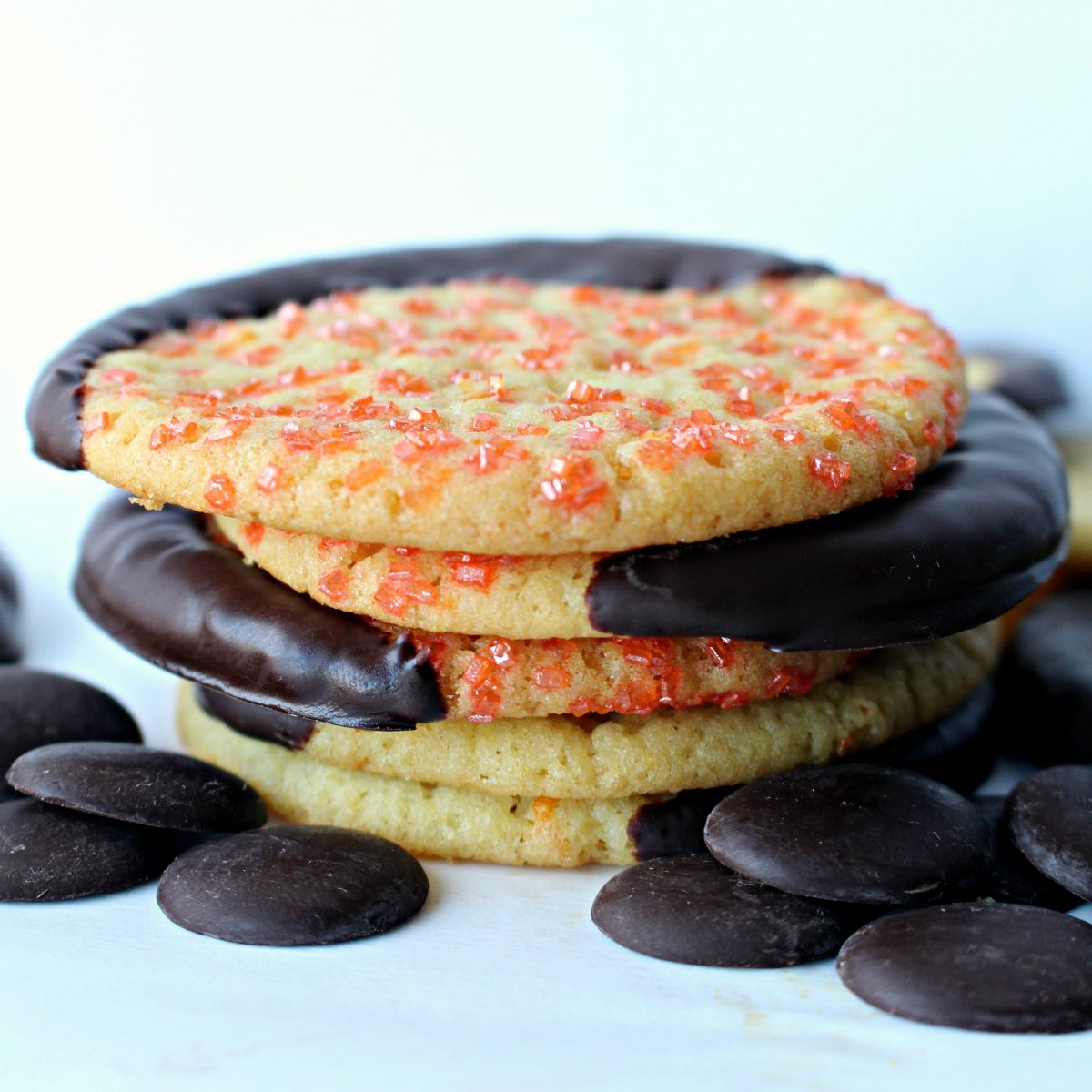Side view of a stack of cookies with orange sugar and an edge dipped in chocolate.