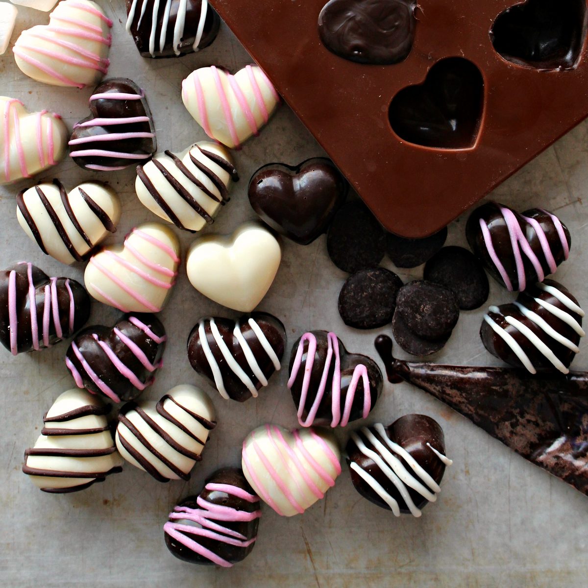 Candies outside of mold in dark and white chocolate with pink or chocolate stripes.