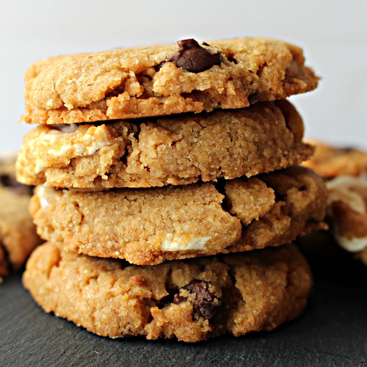 Stack of gluten free s'mores cookies showing thick cookie with chocolate chips and marshmallows.