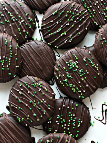 Cookies coated in chocolate topped with chocolate drizzle and sprinkles.