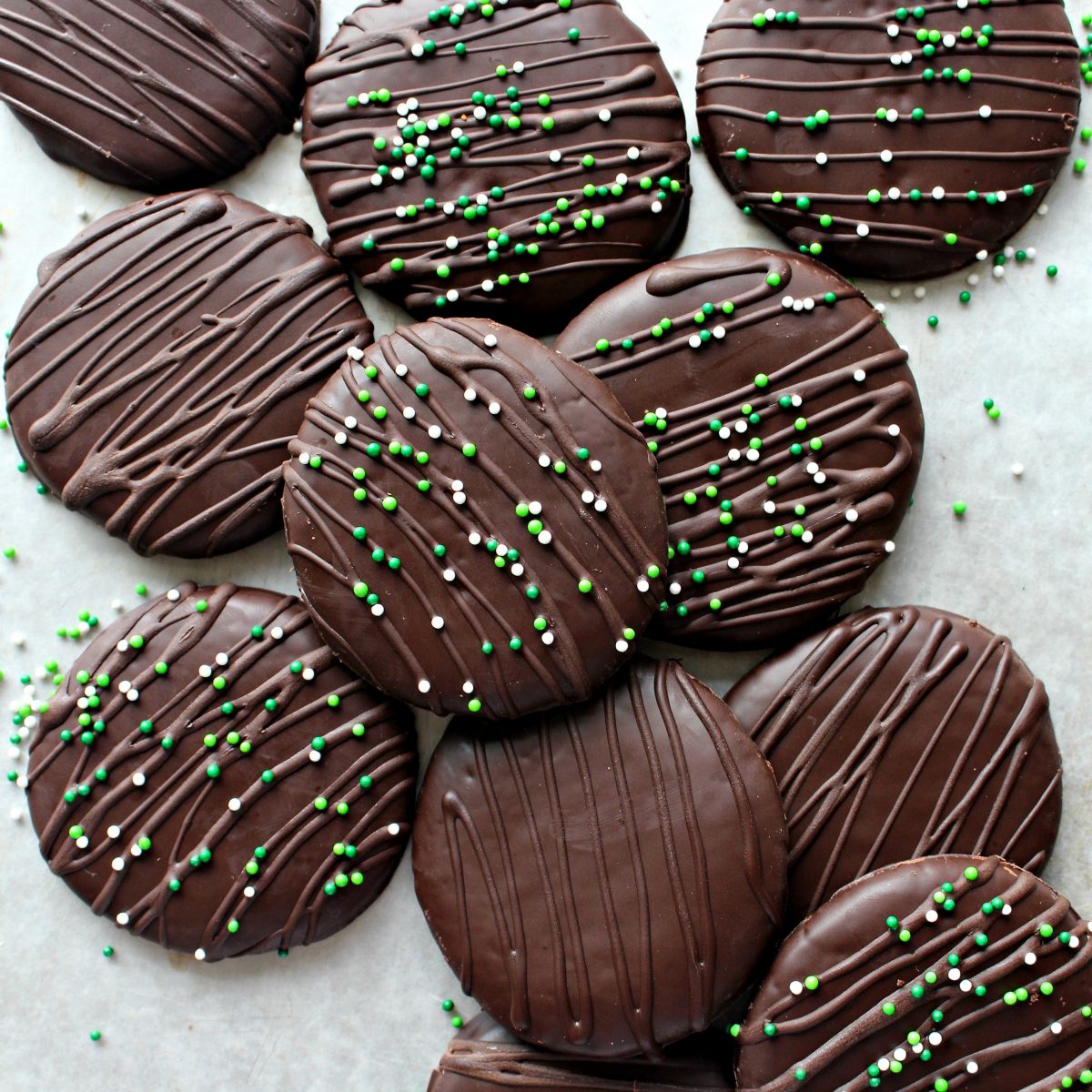Closeup of chocolate covered cookies decorated with chocolate drizzle and sprinkles.