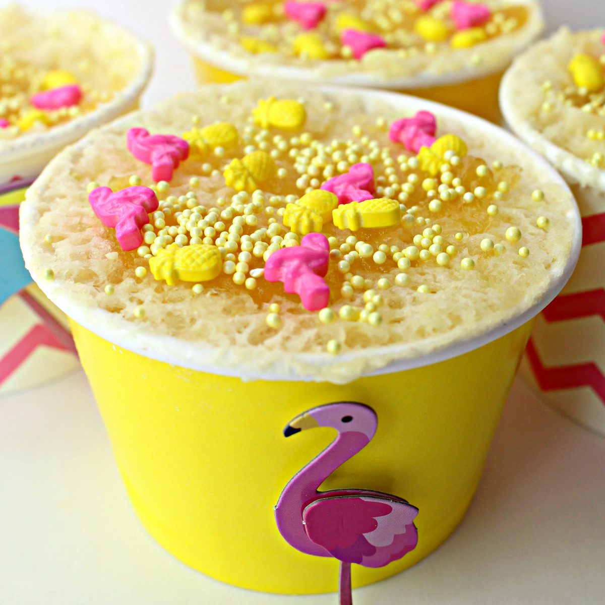 Pineapple Mug Cake in a paper snack cup topped with pineapple and flamingo sprinkles.