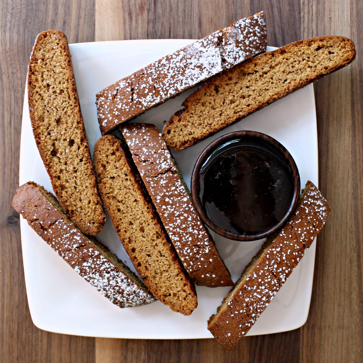 Biscotti on white plate with a bowl of honey.