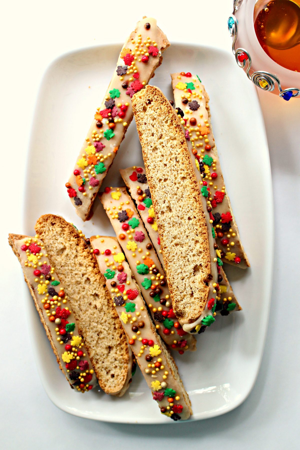 Iced and sprinkled biscotti on a white serving platter.