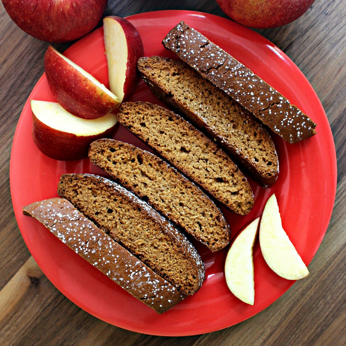 Biscotti on a red plate with apple slices.