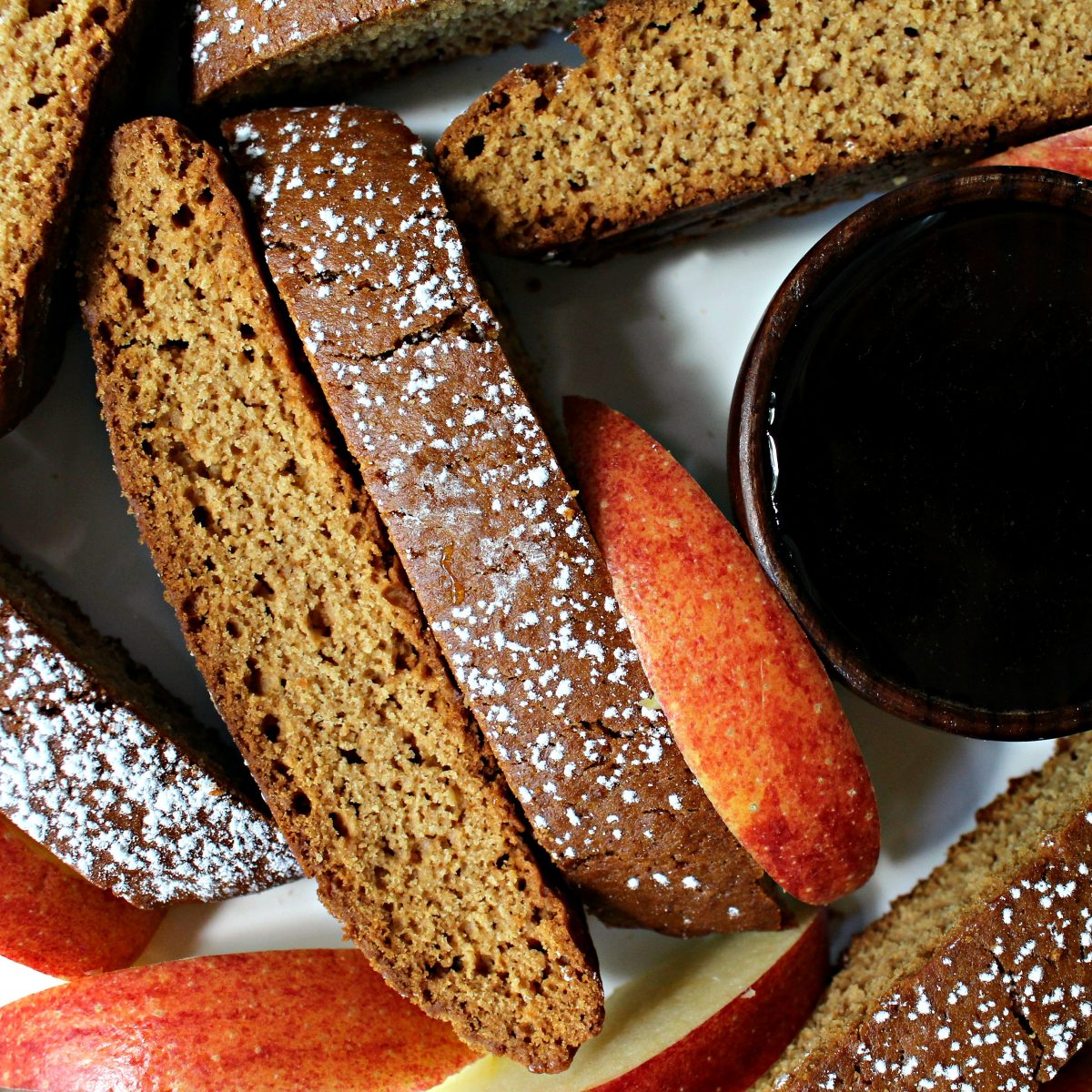 Closeup of biscotti and apple slices next to a bowl of honey.