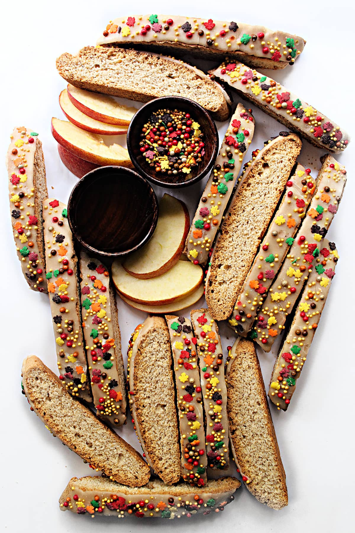 Apple Biscotti with cinnamon icing and fall leaf and pearl sprinkles on a white background.