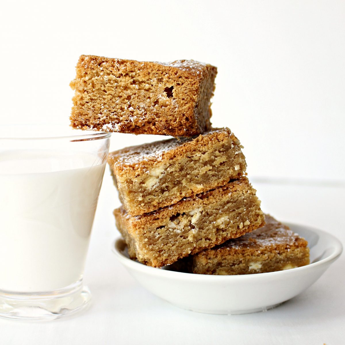 Stack of Root Beer Float Bars leaning on a short glass of milk.