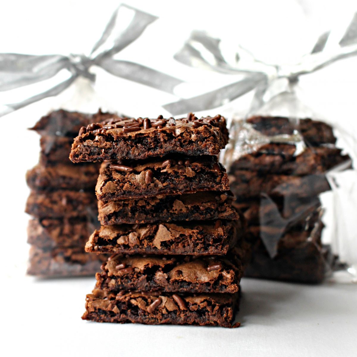 Three stacks of Malted Milk Brownie Bark, two wrapped in cellophane bags with silver bows.
