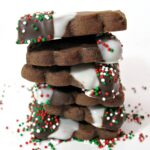 Stack of Chocolate Shortbread Cookies with on end dipped in white and milk chocolate sprinkled with nonpareils.