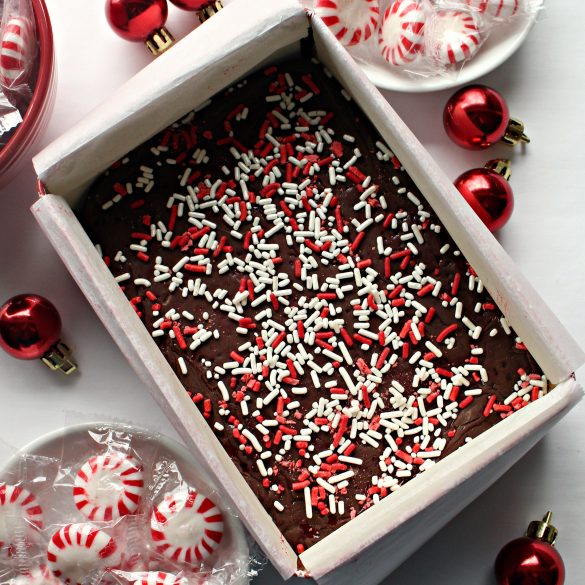 A parchment lined tin filled with fudge topped with red and white sprinkles.