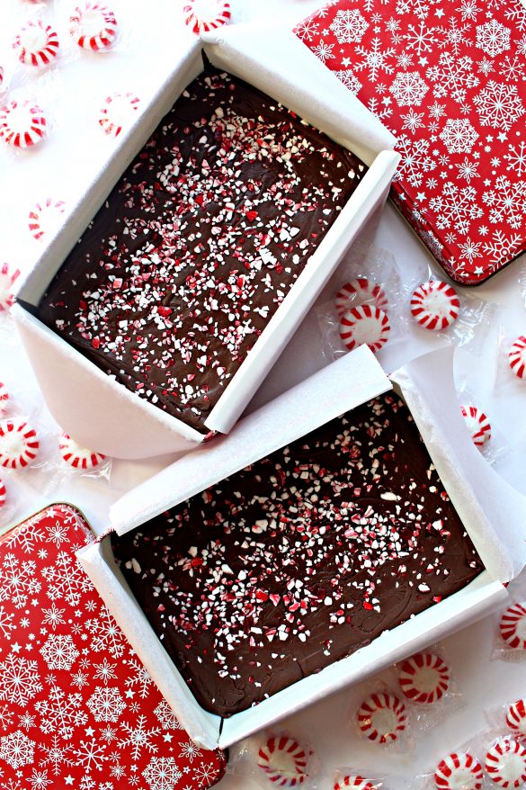 Two open tins filled with Peppermint Fudge, next to the red and white lids.