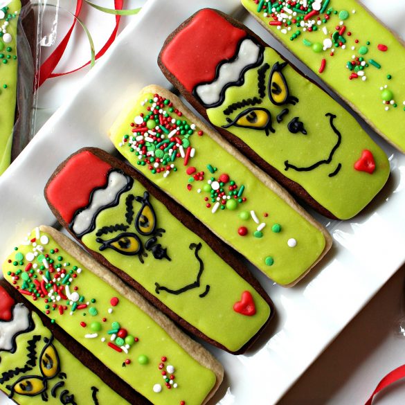 Diagonal photo of Decorated Grinch Cookies and Green Sprinkled Cookies on a white platter.