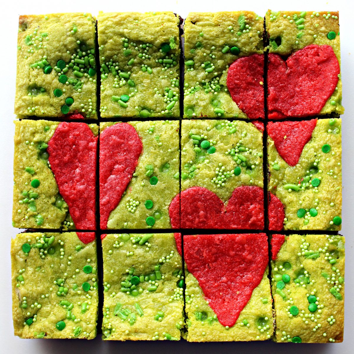 Pan of  green Grinch Brownies with three large hearts on top cut into 12 bars.