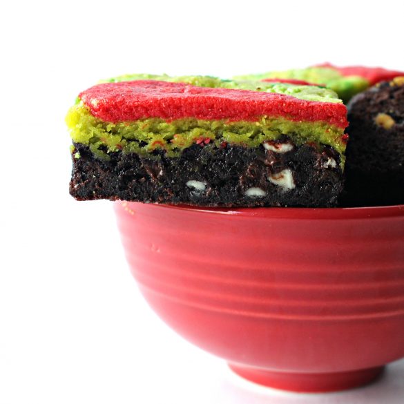 Brownie on top edge of red bowl showing chocolate bottom layer and green and red top.
