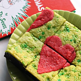 Green Grinch Brownies with a red heart on top on a green plate next to book.