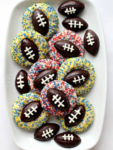 Shortbread Thumbprint Cookies with chocolate footballs in the thumbprint and sprinkles on each cookie.