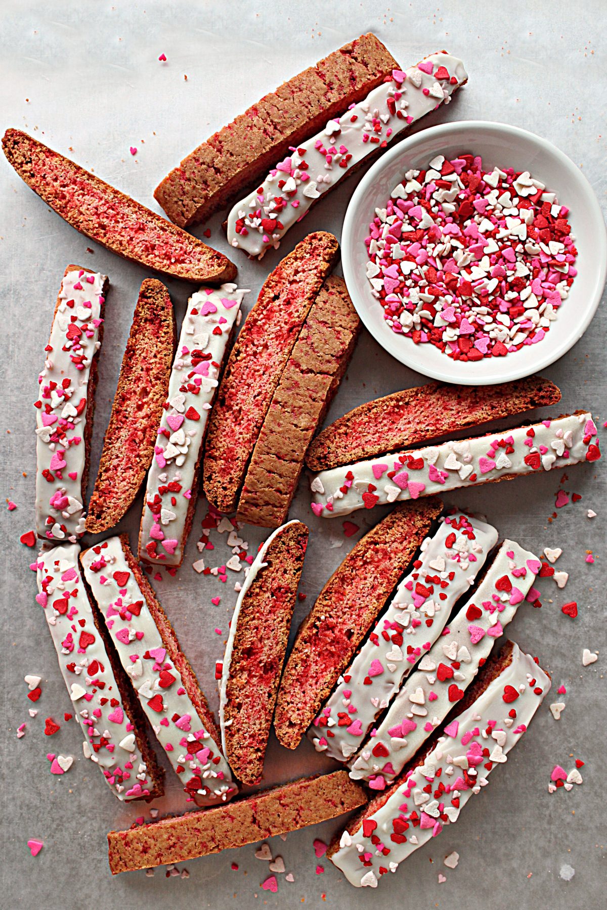 Cinnamon Red Hot Biscotti Cookies on a baking sheet with heart sprinkles.