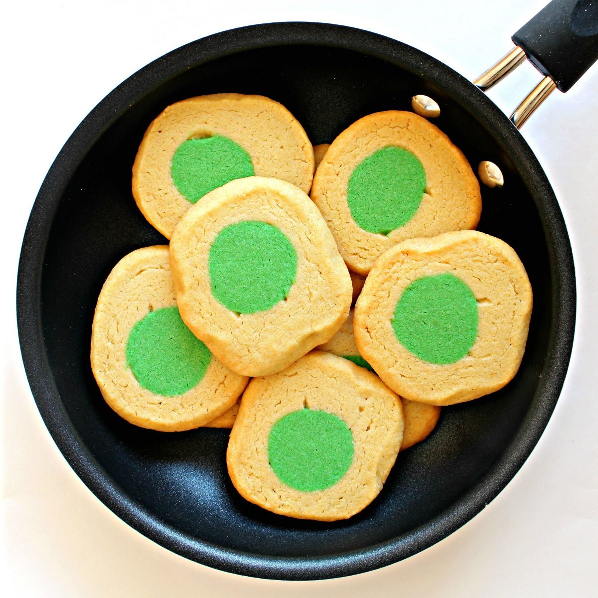 Cookies that look like eggs with green centers in a frying pan.