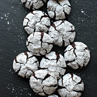Chocolate Crinkle Cookies covered in confectioners sugar on a slate background.
