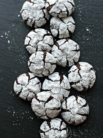Chocolate Crinkle Cookies covered in confectioners sugar on a slate background.
