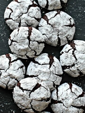 Chocolate cookies coated in powdered sugar with cracks of chocolate showing through.
