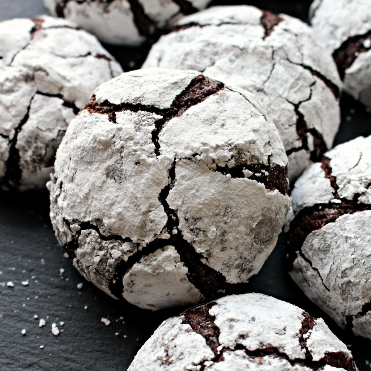 Closeup of Chocolate Crinkle Cookie coated in confectioners sugar with chocolate showing through the cracks.