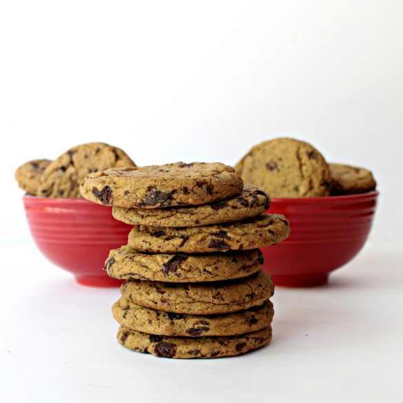 Stack of Chocolate Chip Molasses Cookies in front of two red bowls filled with cookies