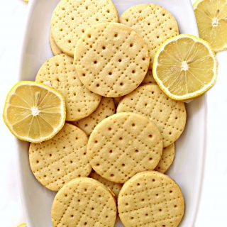 Shrewsbury Biscuits on a white platter with a few slices of lemon