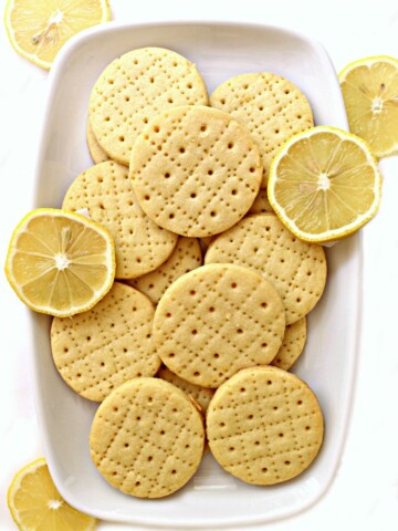 Shrewsbury Biscuits on a white platter with a few slices of lemon