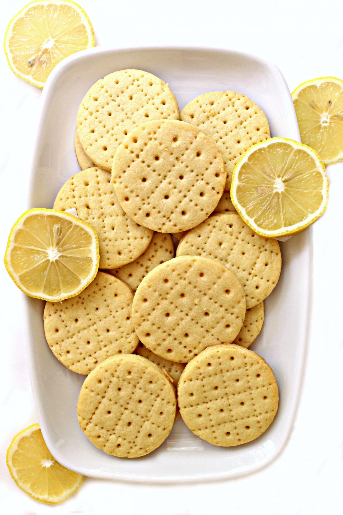 Shrewsbury Biscuits on a white platter with a few slices of lemon.