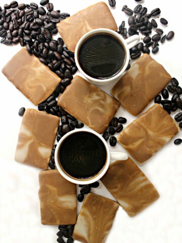 Coffee Cookies with brown and white marbled icing on a white background with coffee beans and 2 white mugs of espresso
