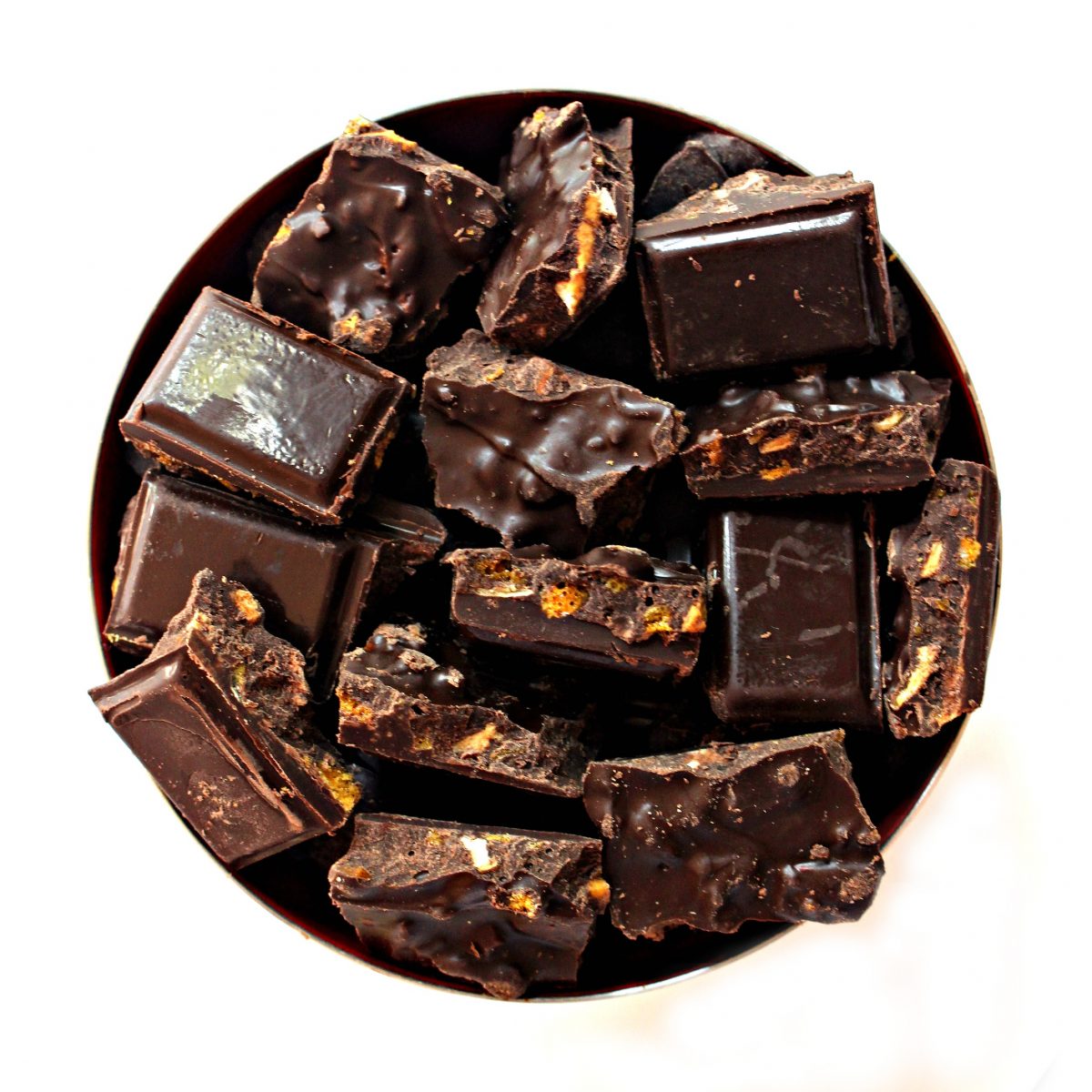 Overhead photo of chocolate bar pieces in a bowl, showing bits of apple and honeycomb inside.