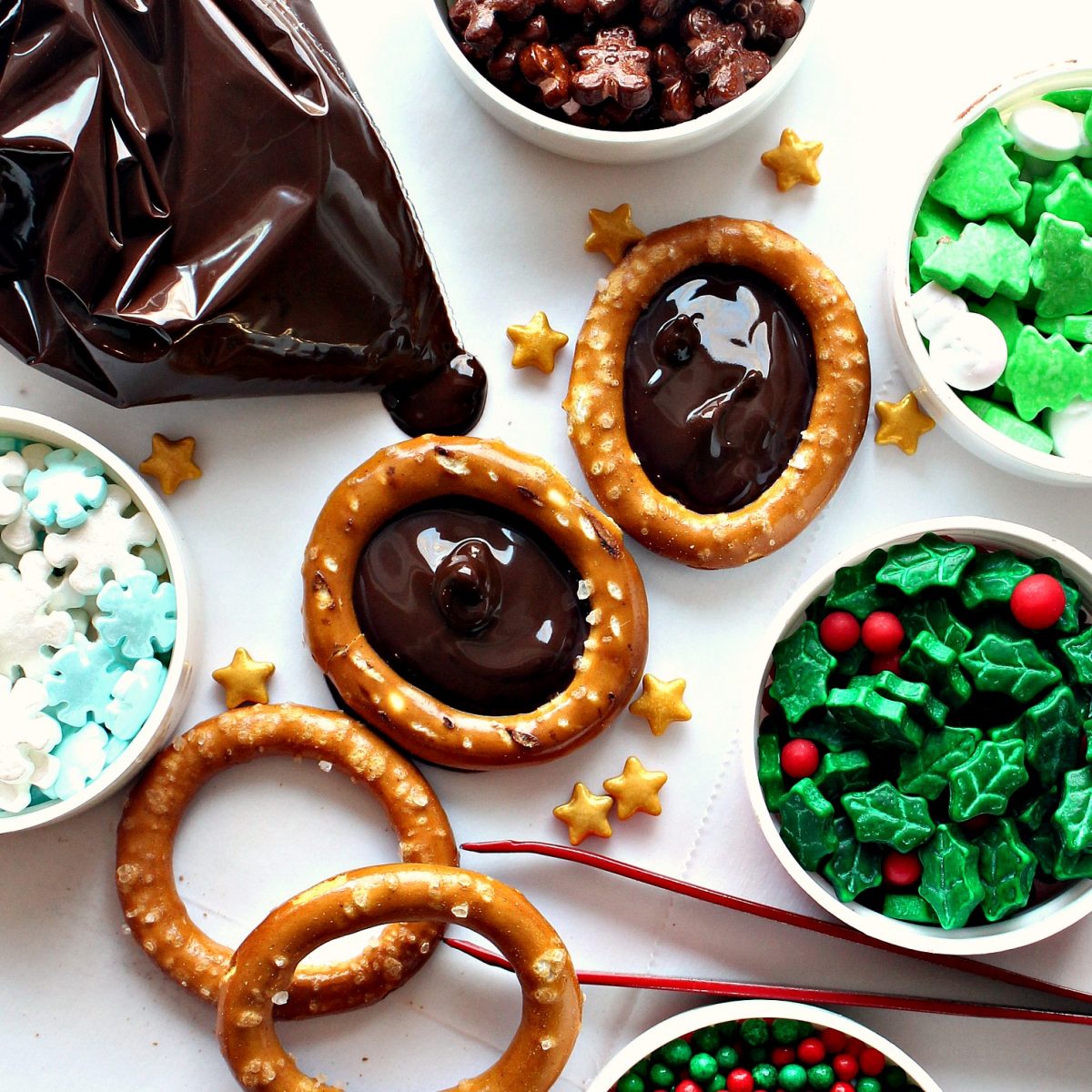 Pretzel rings with centers filled with melted chocolate surrounded by sprinkles for decorating.