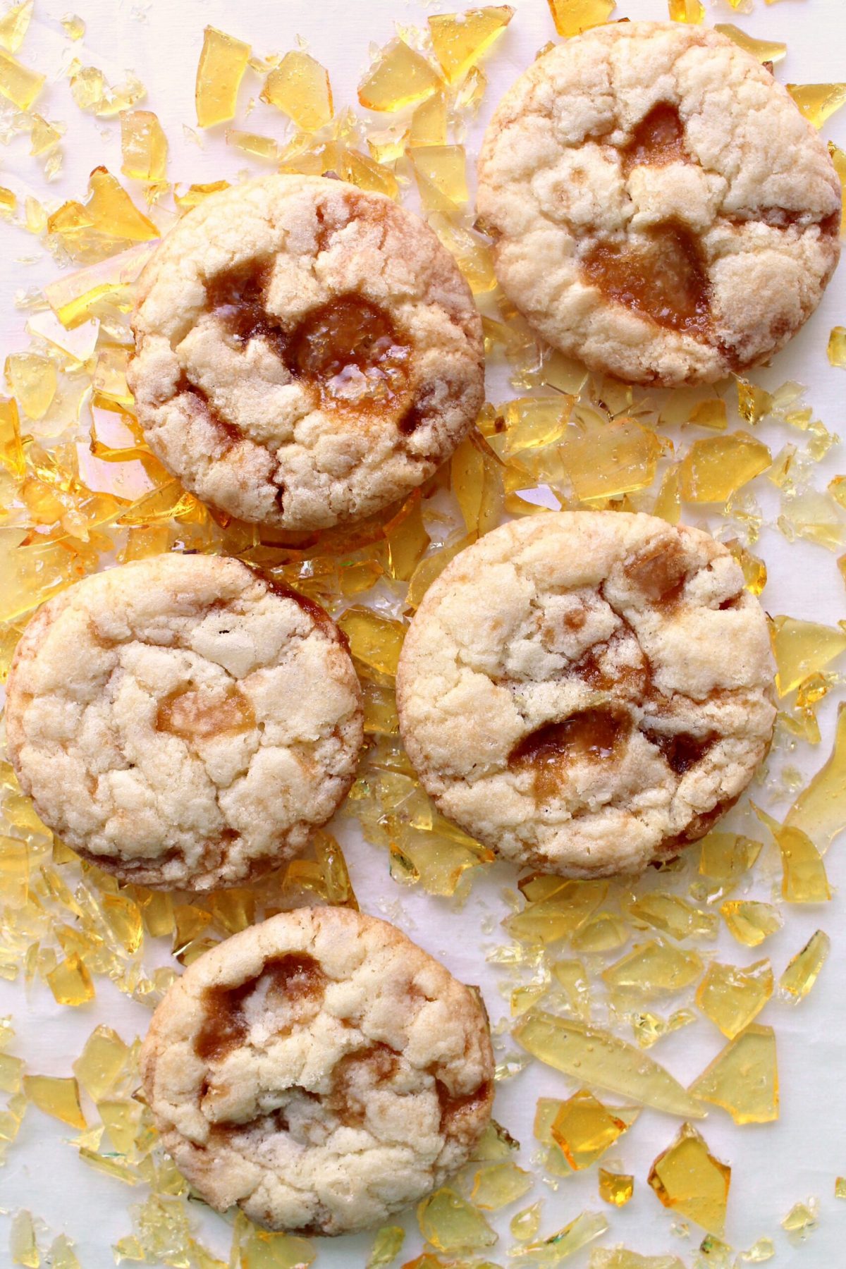 Butter cookies, with pools of melted caramel on top, lying on shards of caramel candy.