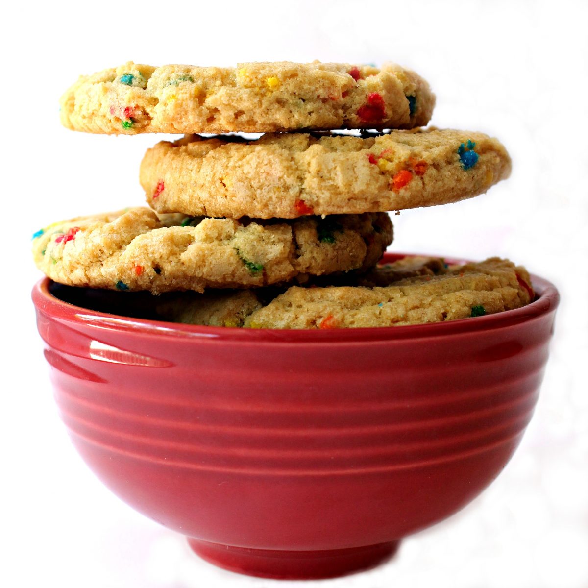 Side view of stack of cookies in a red bowl showing the thick, rounded edges of the cookies.