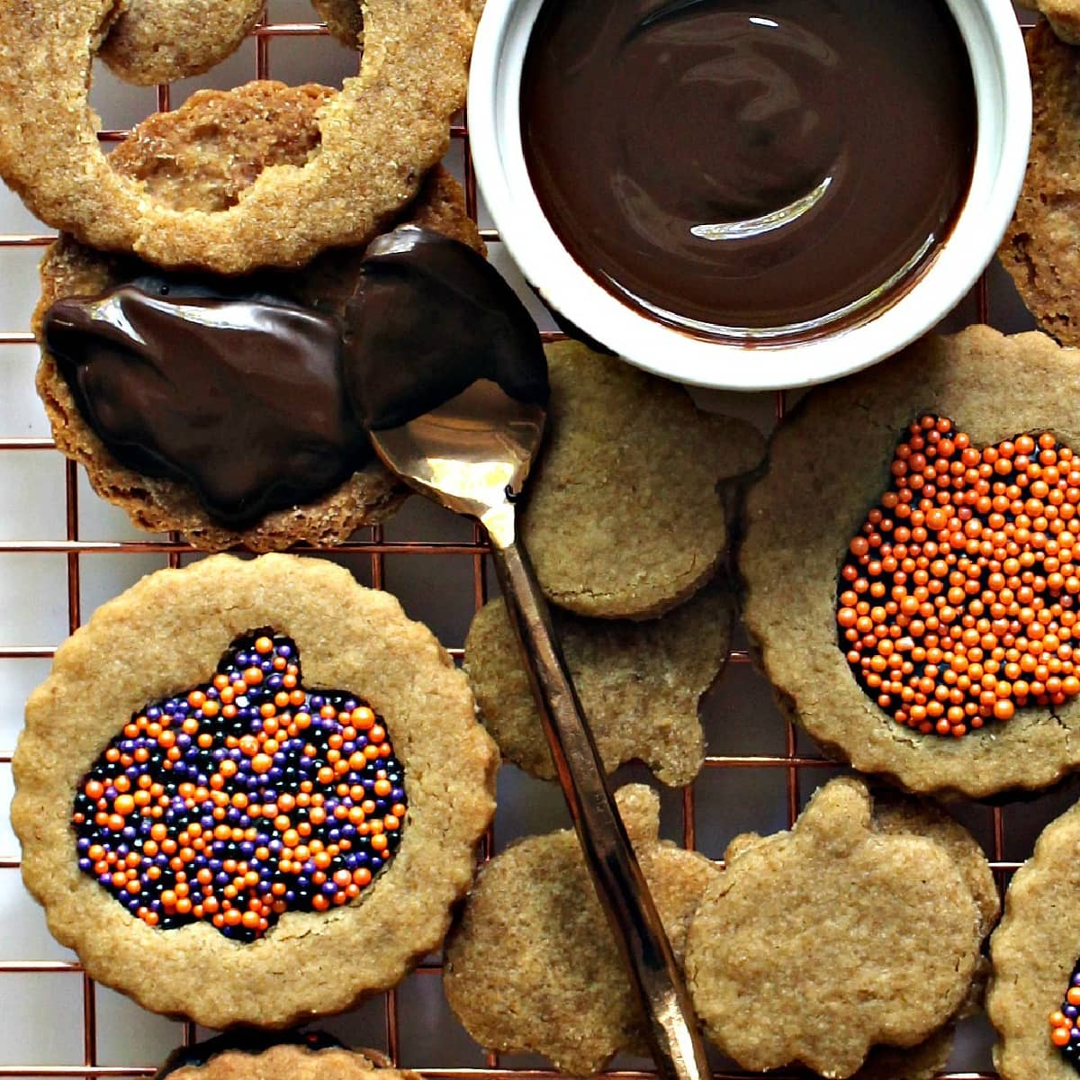 Close up of graham cookies sandwiched with melted chocolate peeking through a pumpkin cutout with sprinkles.