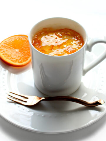 Orange Mug Cake in a white mug topped with orange marmalade.