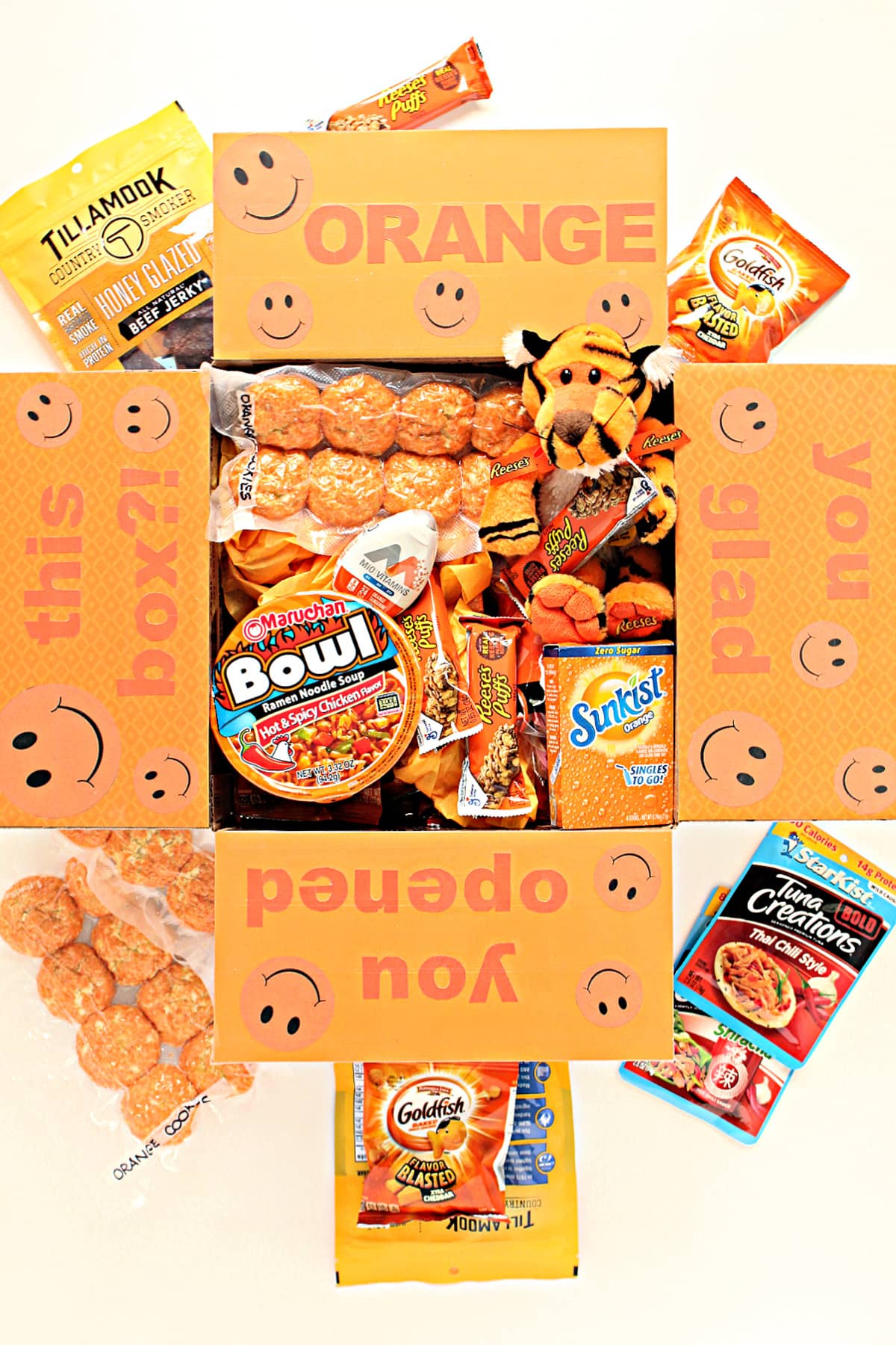 Care package box filled with orange packaged treats and orange box decorated box flaps.