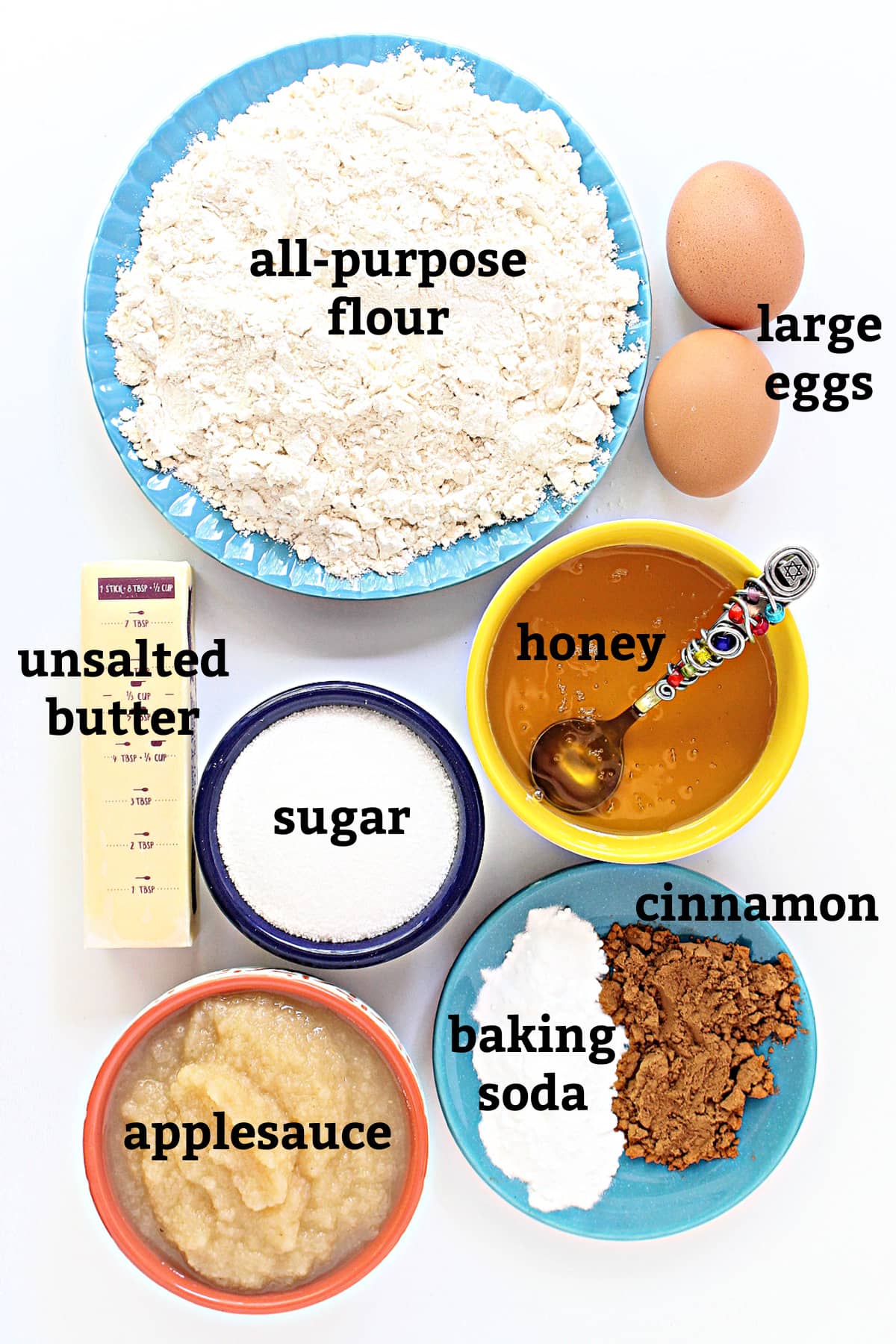 Honey Cake ingredients with labels; flour, eggs, unsalted butter, honey, sugar, applesauce, baking soda, cinnamon.