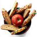 Apple biscotti in a bowl with an apple.