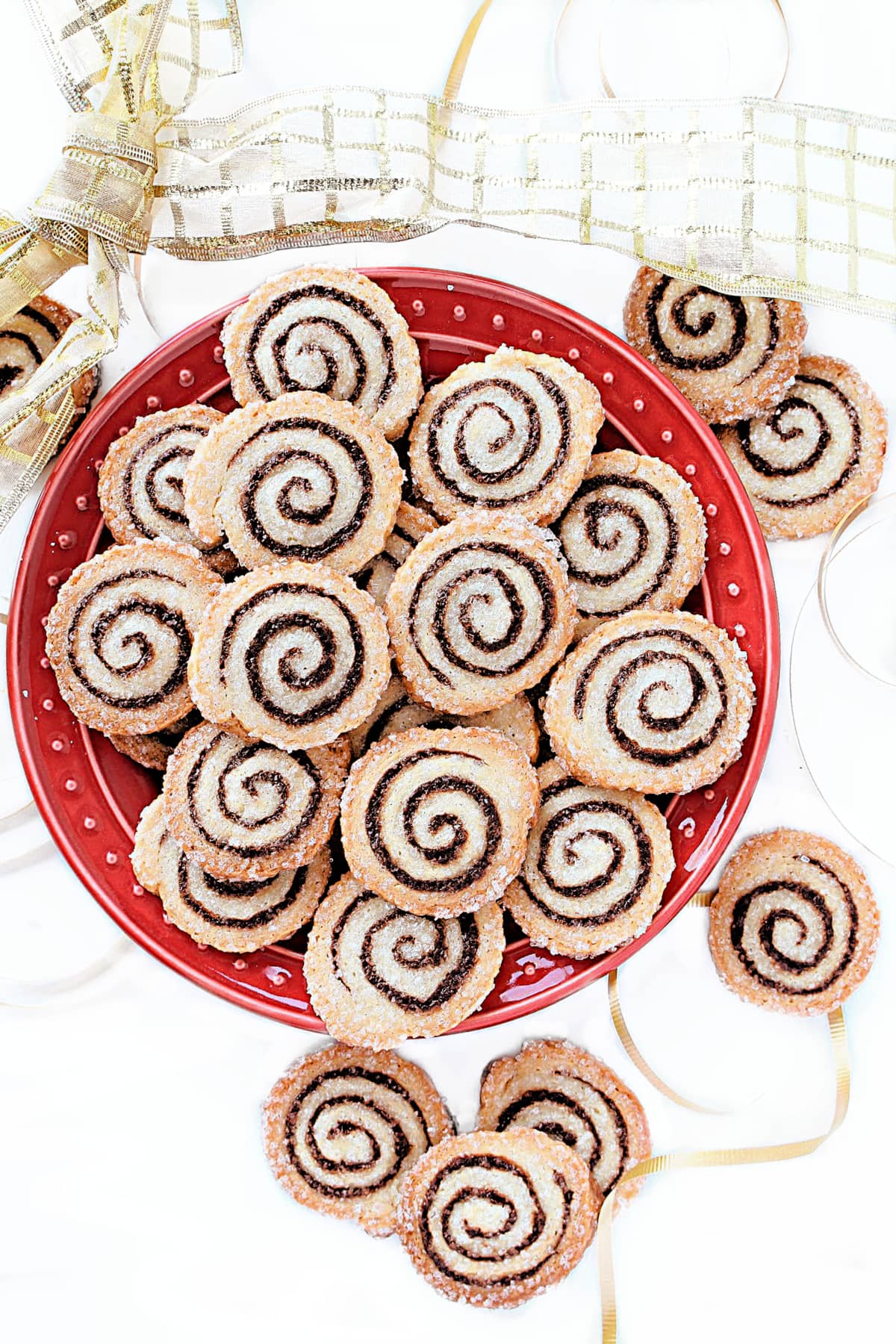 Golden brown cookies coated in sugar with a spiral of chocolate filling on a red plate.