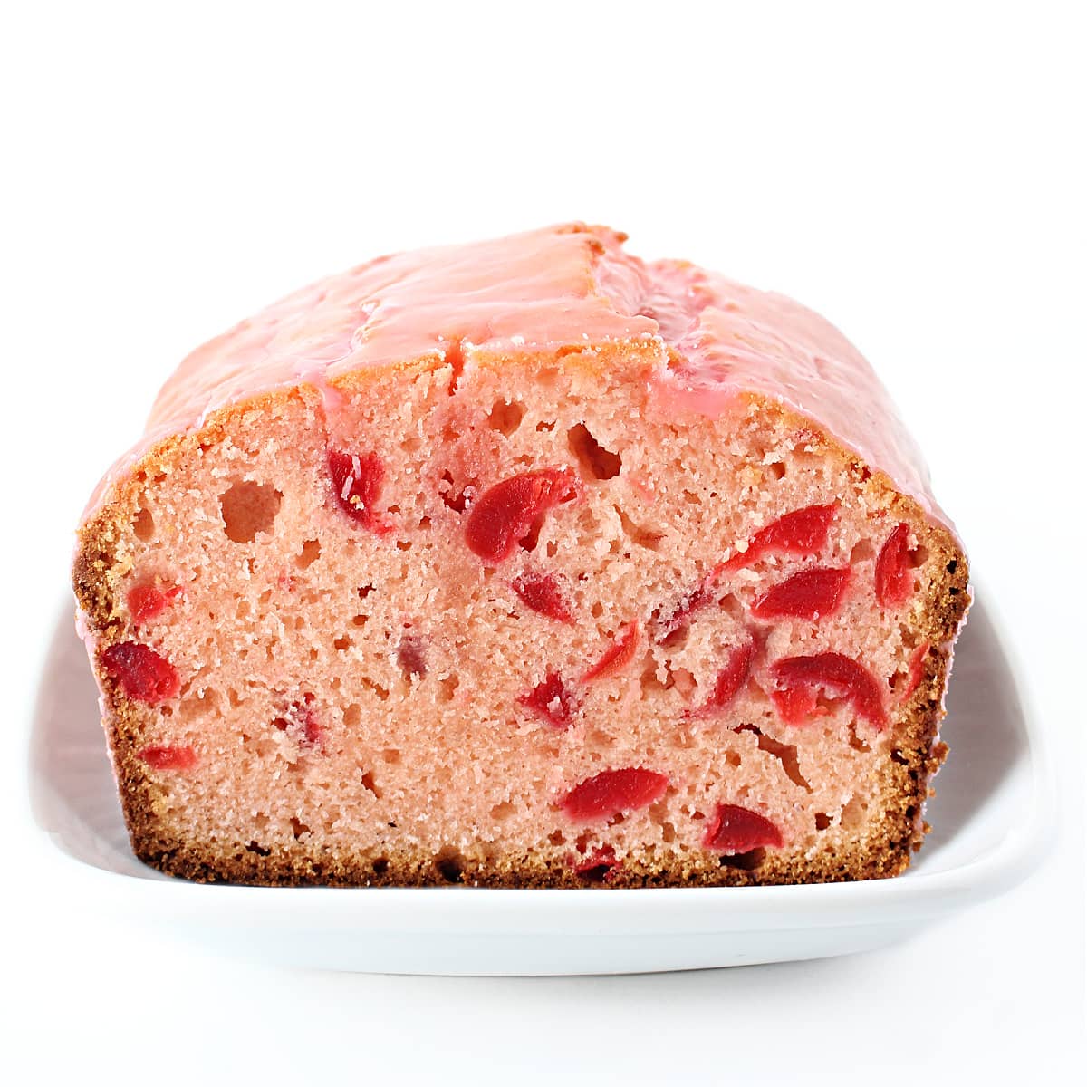 Cherry loaf with a slice removed to show interior pink cake with cherry bits.