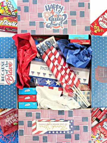 4th of July Care Package decorated and filled with decorations and foods in red, white, and blue.